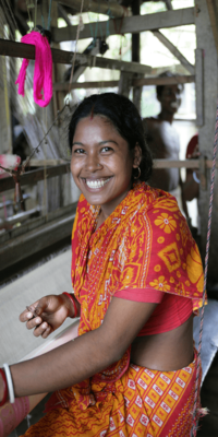 Smiling woman in orange at a loom